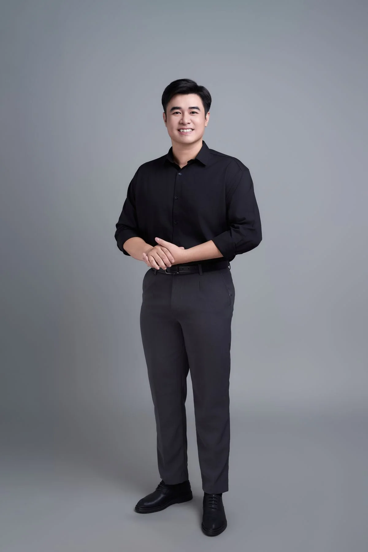 灰色影棚中微笑站立的男士原始照片